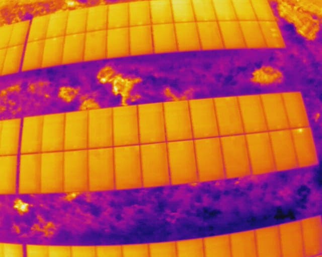 Aerial thermal frame of two rows of solar modules in the ironbow palette, from a public CC0 dataset